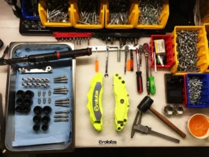 A close-up of a precision-machined metal part resting on a work surface, showing detailed tooling marks and edges.